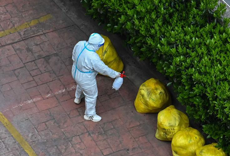 2022年4月3日,一名身穿防护服的志愿者给垃圾袋子喷洒消毒剂.